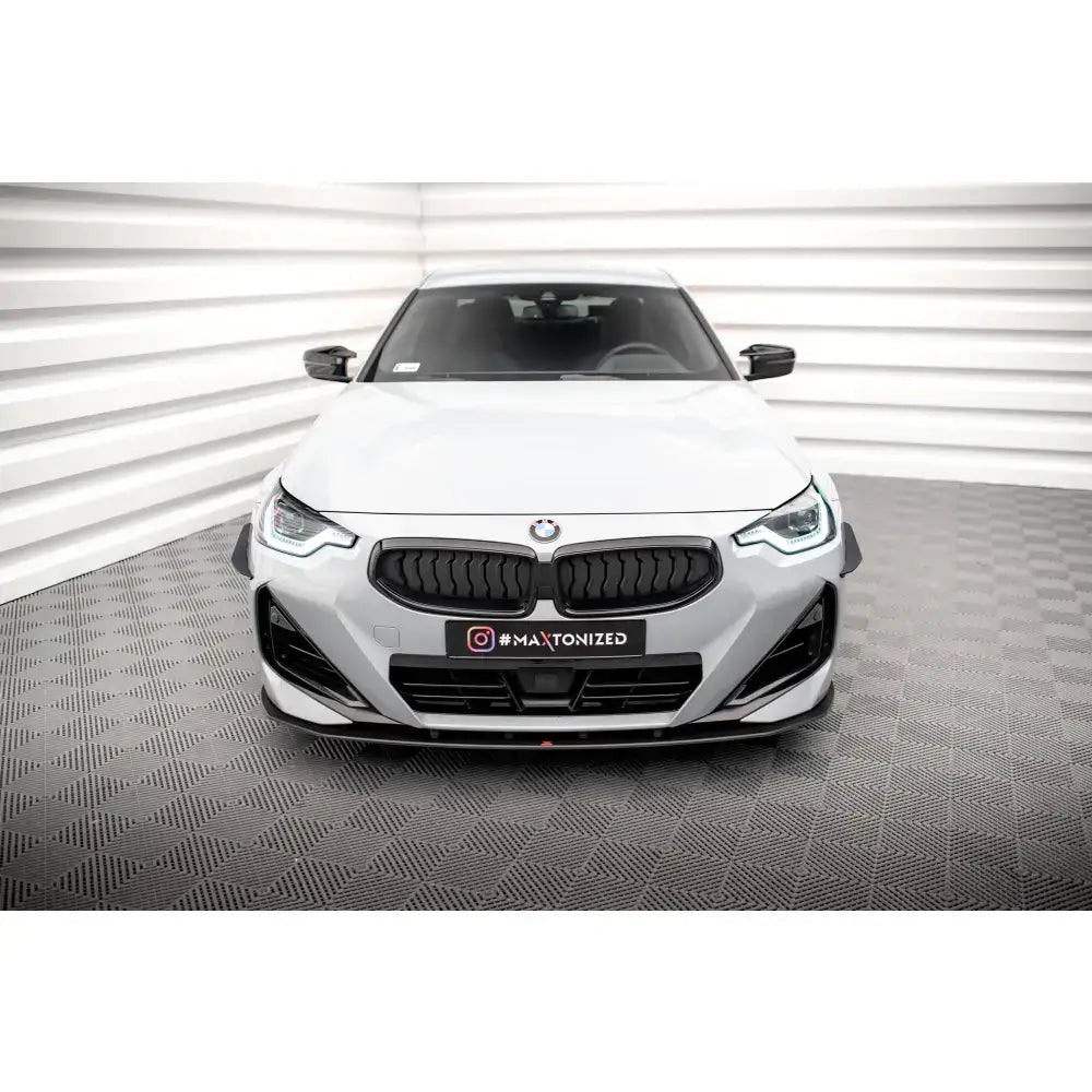 Spoiler på BMW 2 Coupe M-Pack G42 med sorte detaljer og LED-lys, sett forfra på mønstret gulv.