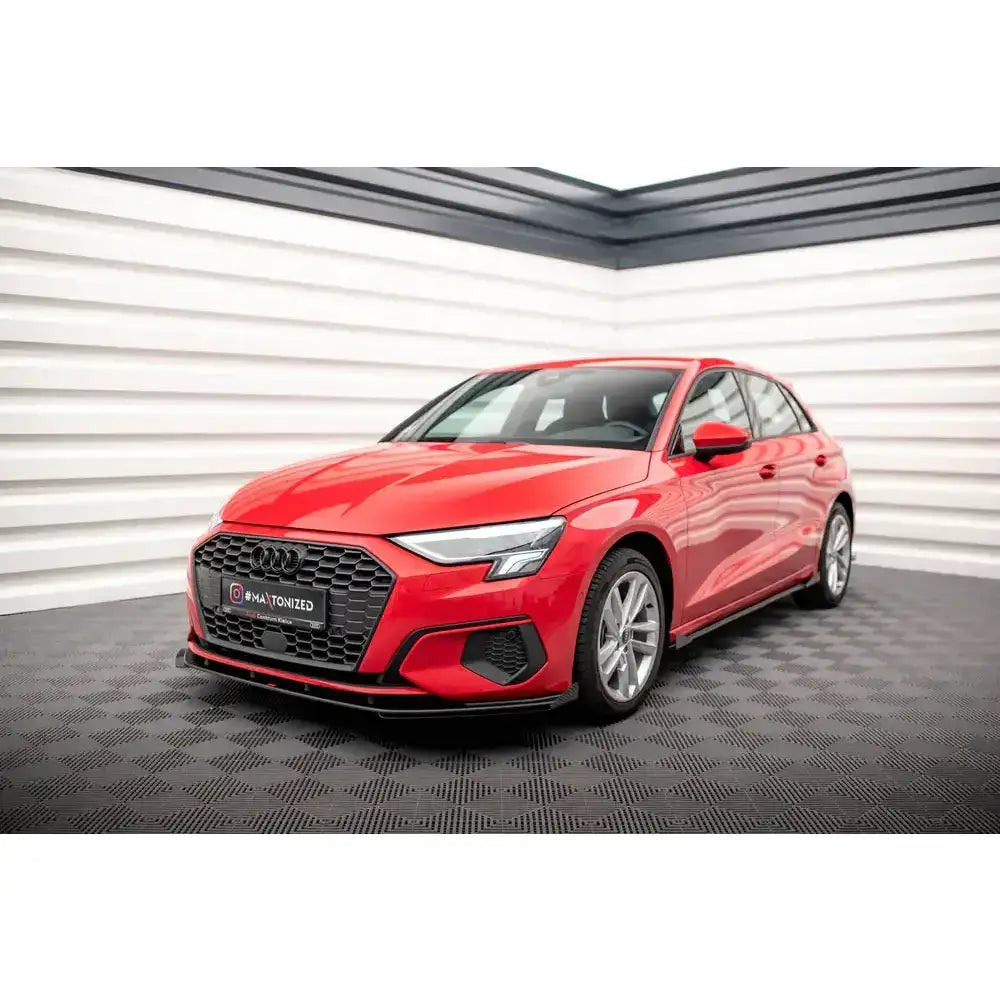 Front lip på Audi A3 8Y Street Pro med flaps, rød bil med sort grill og sølvfelger innendørs.