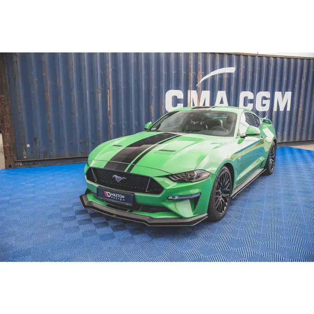 Frontleppe på Ford Mustang GT MK6 Facelift med sorte striper, svarte felger og blå container i bakgrunnen.