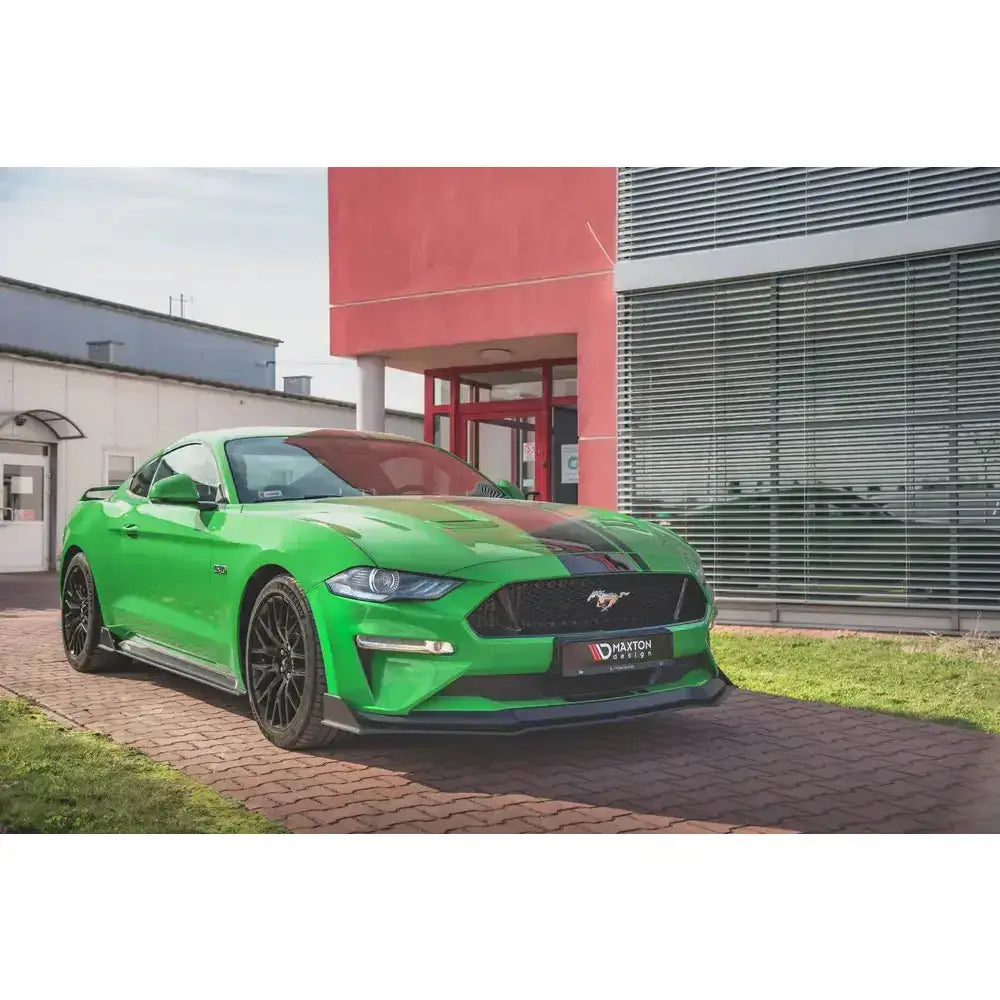 Frontleppe på grønn Ford Mustang GT MK6 Facelift med svarte detaljer, parkert foran moderne bygning.