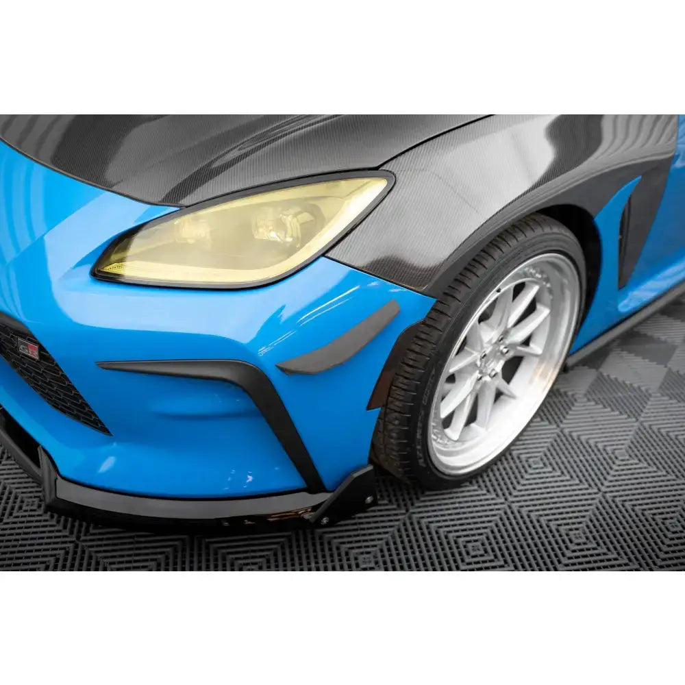 Front splitter på Toyota GR86 Mk1 med blå lakk, karbonfiberpanser og gule frontlys sett fra venstre.