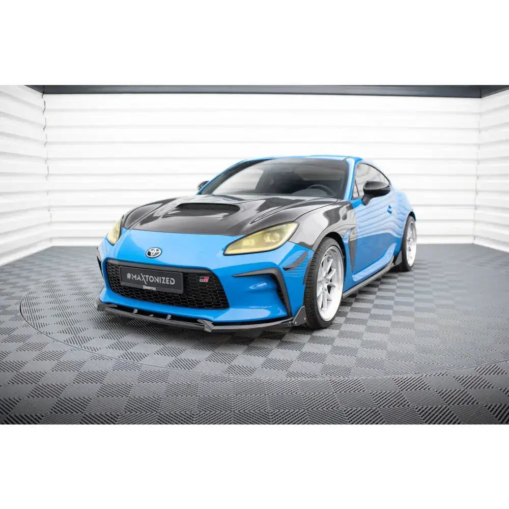 Frontspoiler på blå Toyota GR86 Mk1 med sort panser og gule frontlykter, sett skrått forfra.