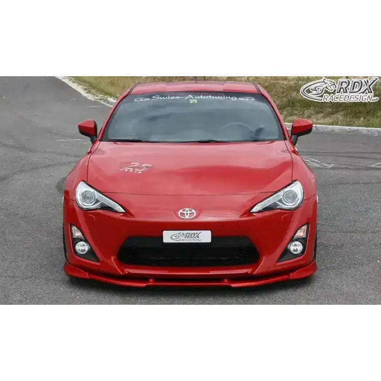 Front splitter på rød Toyota GT86 V.2 med sorte detaljer, lav spoiler og tydelige frontlykter parkert på asfalt.