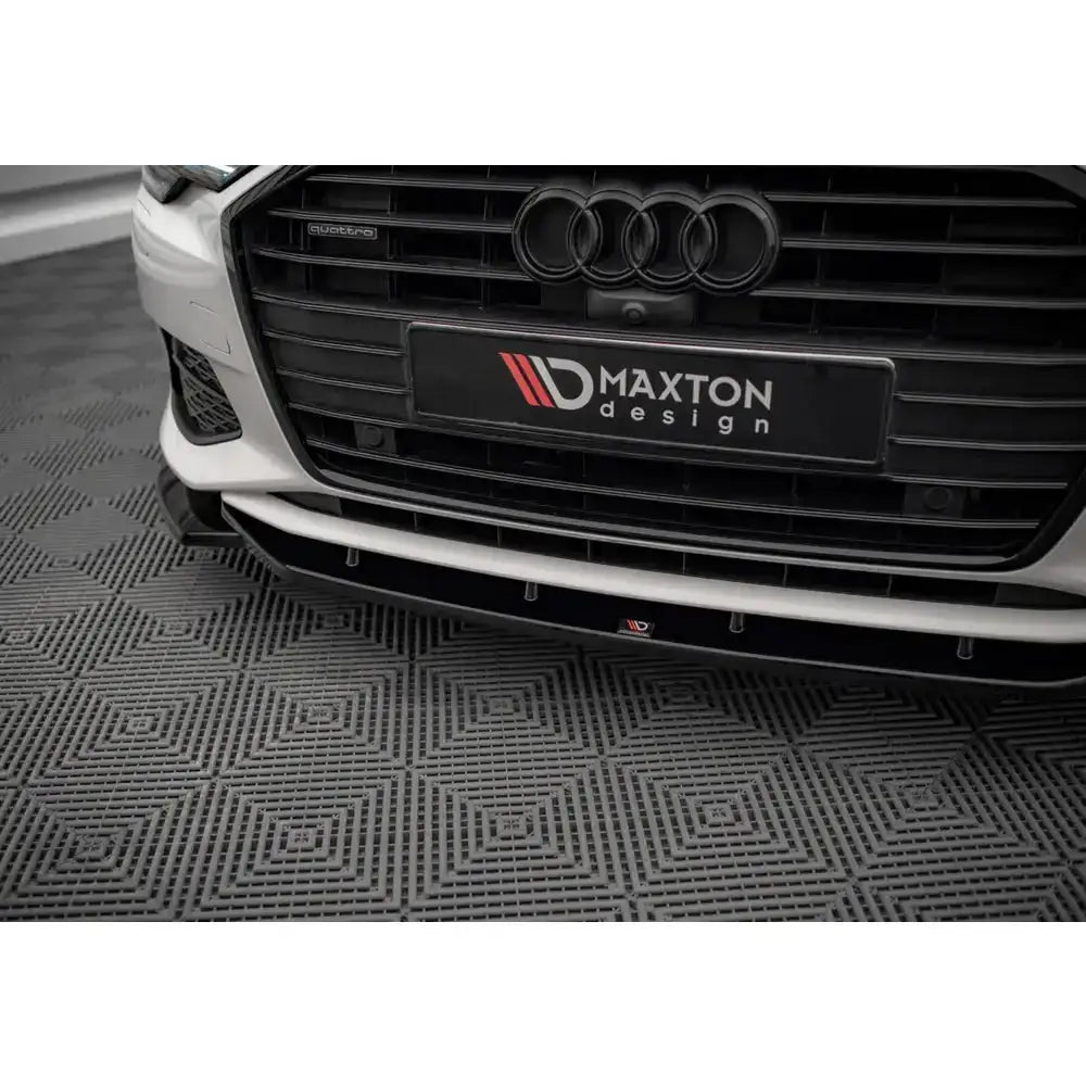 Spoiler til Audi A6 C8 V.1 i sort plast montert foran, sett skrått nedenfra med synlig Maxton Design-logo.