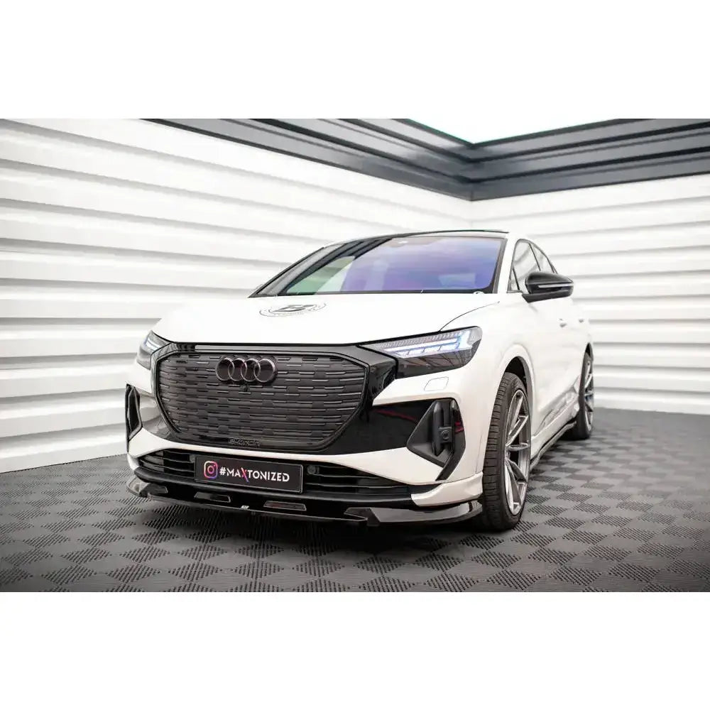 Frontleppe på Audi Q4 e-tron Sportback Mk1 med sort grill og sportsfelger i lyst industrilokale.