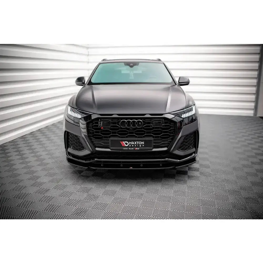 Frontspoiler på Audi RSQ8 Mk1 19- sett forfra med sort grill og bikubemønster i lyst rom.