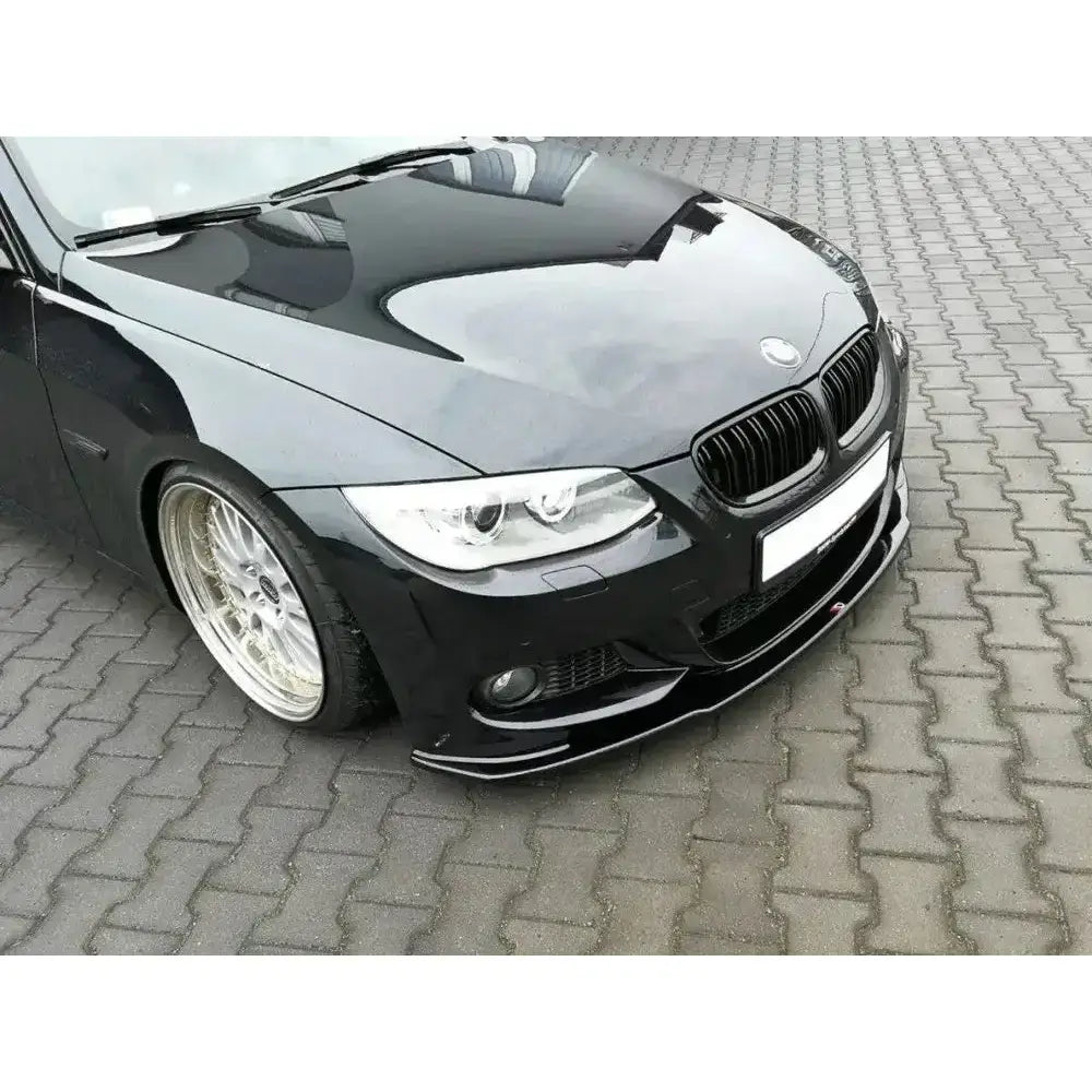 Front splitter på sort BMW 3 E92 M-Pack Facelift med store sølvfelger, sett skrått forfra på brostein.