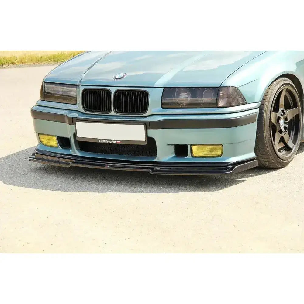 Frontspoiler BMW M3 E36 V.1 montert på blågrønn bil med svarte detaljer og gule tåkelys.