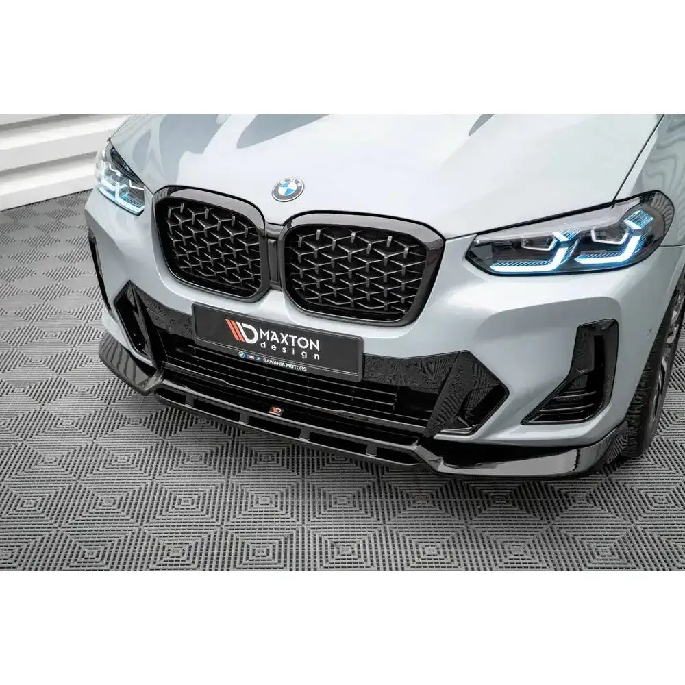 Front splitter på BMW X4 M-Pack G02 Facelift med svarte detaljer og blå LED-frontlykter, sett skrått forfra.