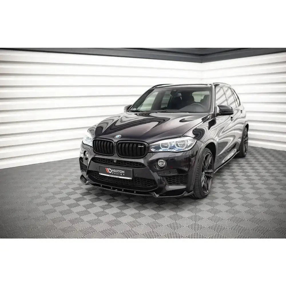 Frontleppe på BMW X5 M F15 SUV i sort med LED-lykter, sett forfra fra venstre side i lyst rom.