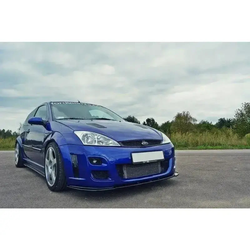 Front splitter på blå Ford Focus Mk1 RS med brede skjermer og store felger, sett forfra utendørs.