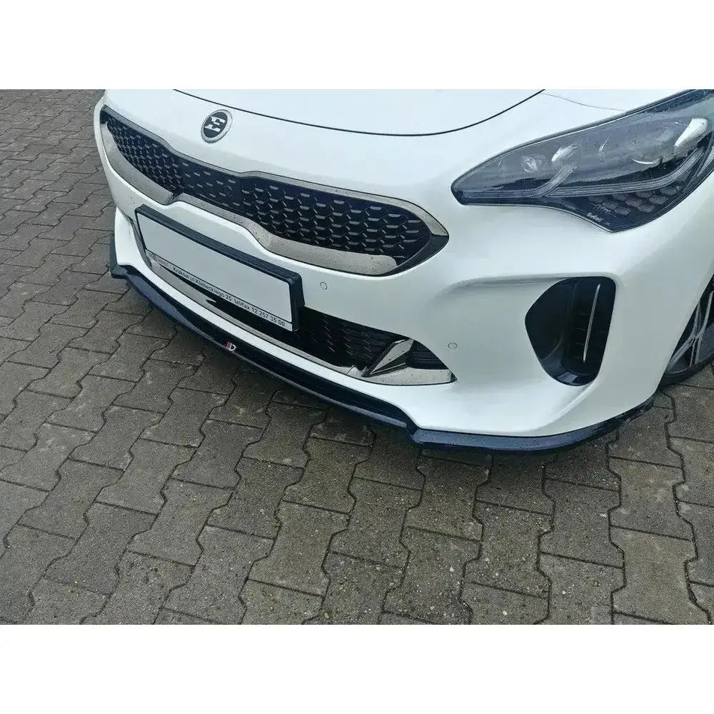 Frontspoiler Kia Stinger GT V.1 montert under støtfanger på hvit bil med svart grill, parkert på brostein.
