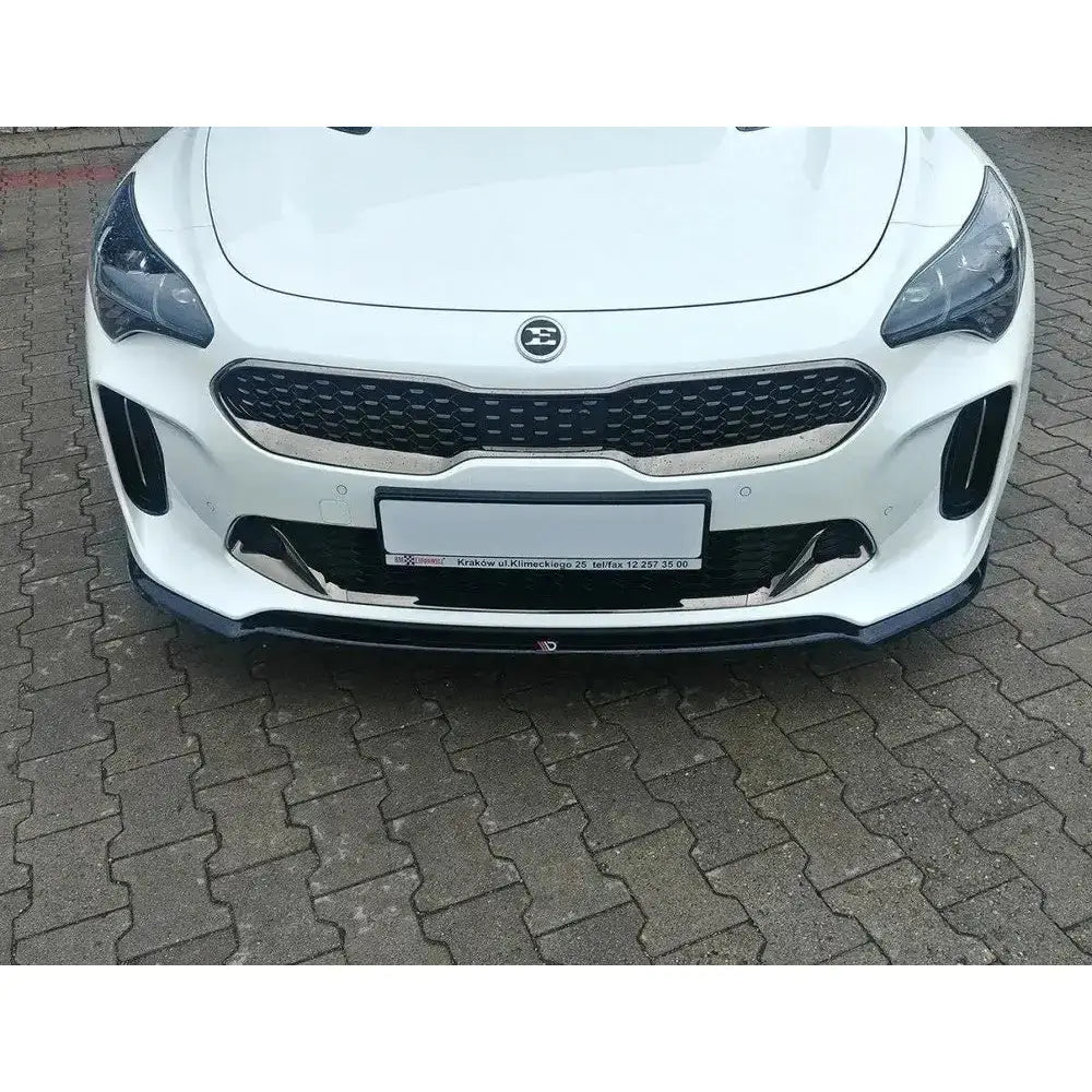 Spoiler på Kia Stinger GT V.1 med sort grill og markert frontleppe, parkert på brostein.