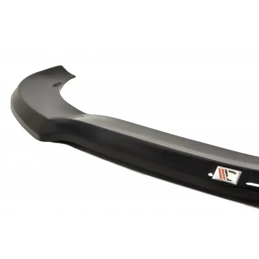 Front lip Mercedes CLA 45 AMG C117 V.1 i sort plast med metallogo, skrå sidevisning mot hvit bakgrunn.