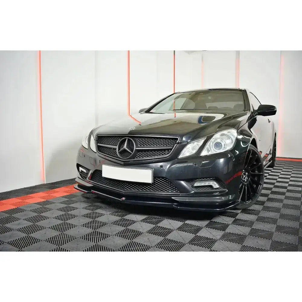 Frontspoiler på Mercedes E-Klasse W207 Coupe AMG Line med store felger på sjakkmønstret gulv.