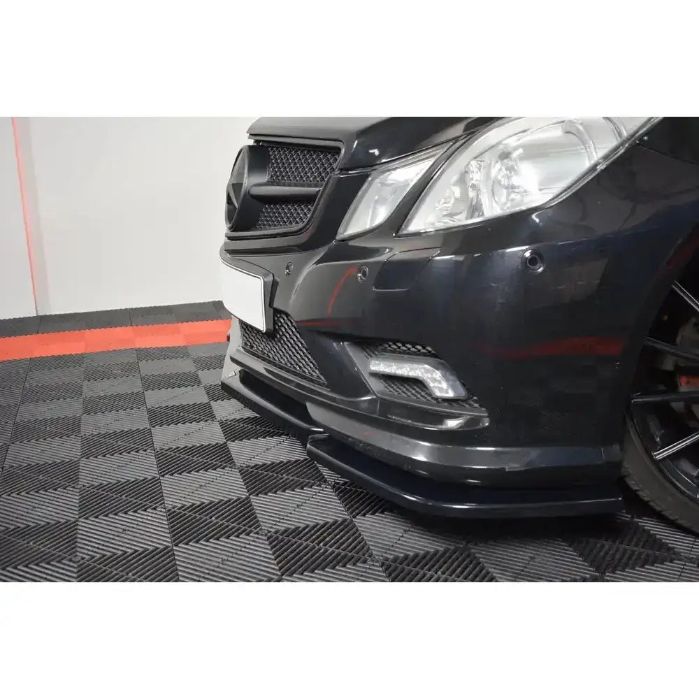 Front splitter til Mercedes E-Klasse W207 Coupe AMG Line, glanset sort med rutenett og LED-lys montert foran.