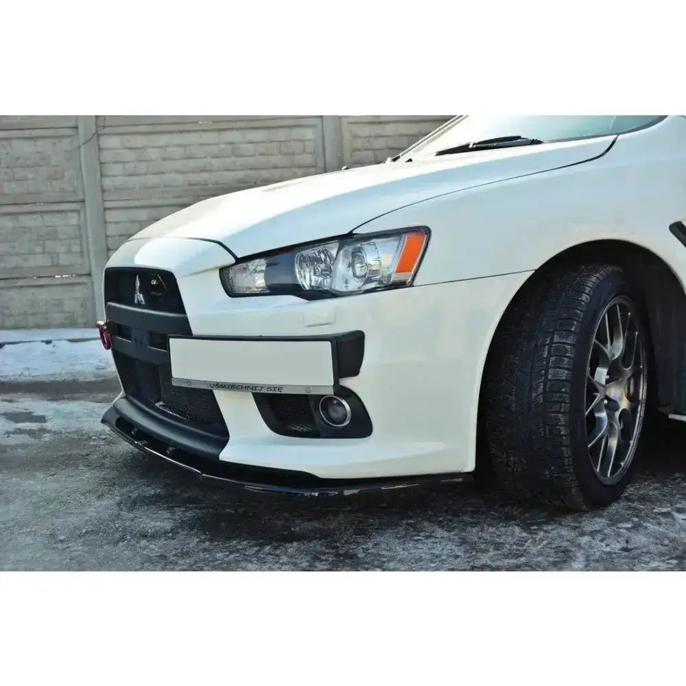 Front lip på Mitsubishi Lancer Evo X V.1, hvit bil sett skrått fra siden med sorte detaljer og frontlys.