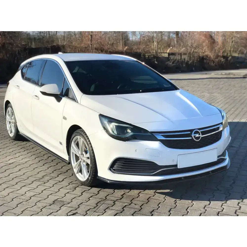 Frontleppe på Opel Astra K Opc-Line, hvit bil med sorte felger og kromdetaljer parkert på steinlagt område.