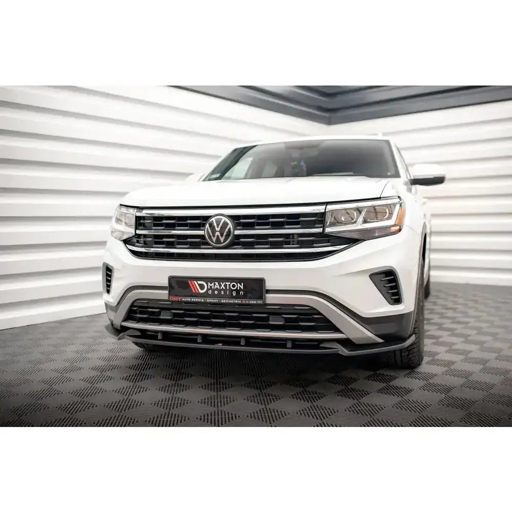 Front splitter på Volkswagen Atlas Cross Sport med sort grill og Maxton Design-logo, sett forfra innendørs.
