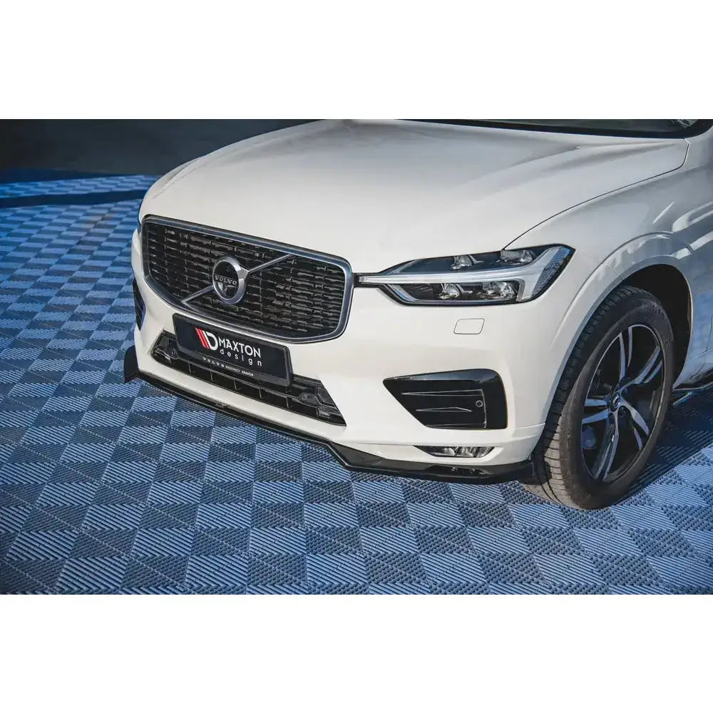 Front splitter på Volvo XC60 Mk2 V.1 R-Design med svart grill, lykter og sorte felger på blåmønstret gulv.
