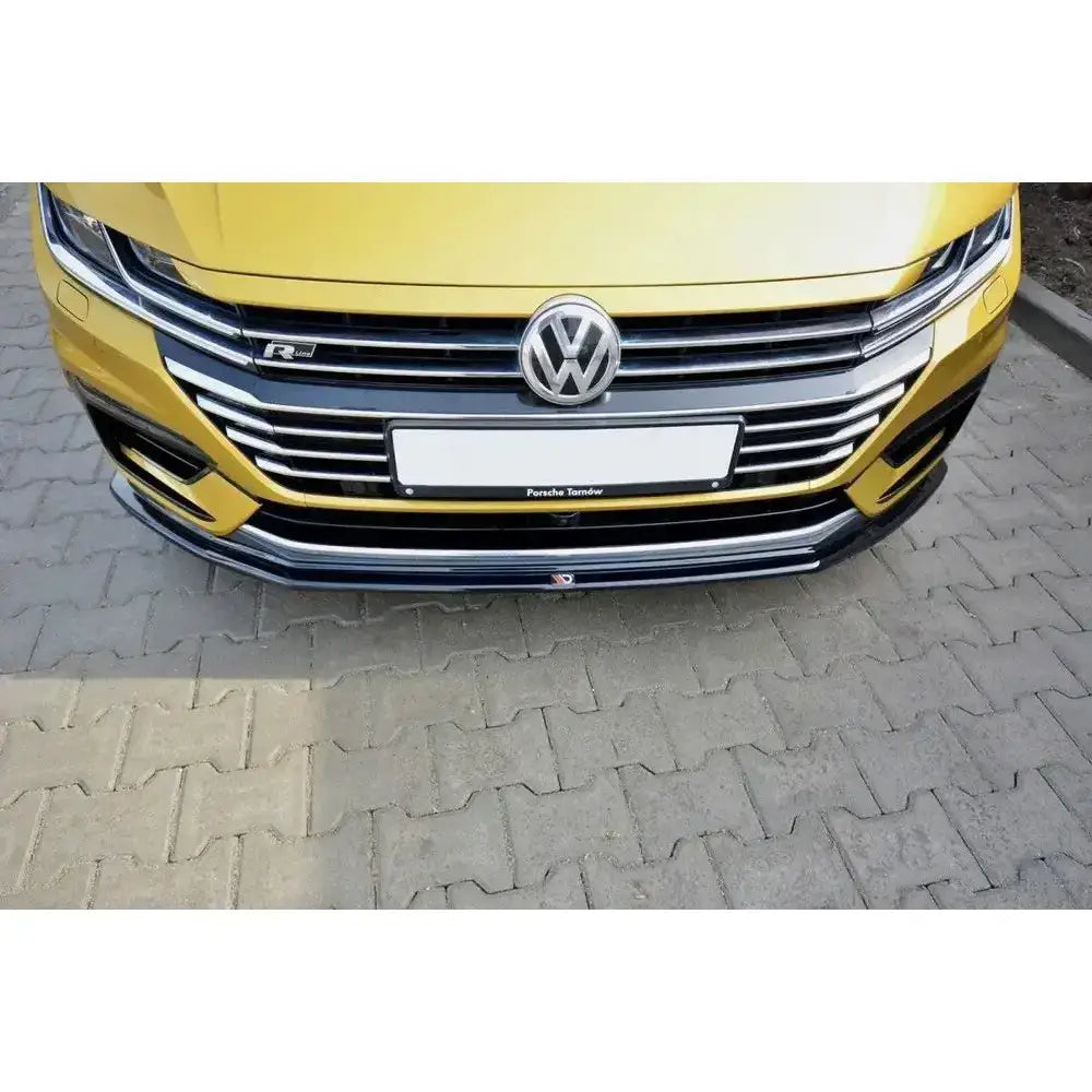 Spoiler på VW Arteon V.1, nærbilde av gul bilfront med kromgrill, sort leppe og VW-logo.