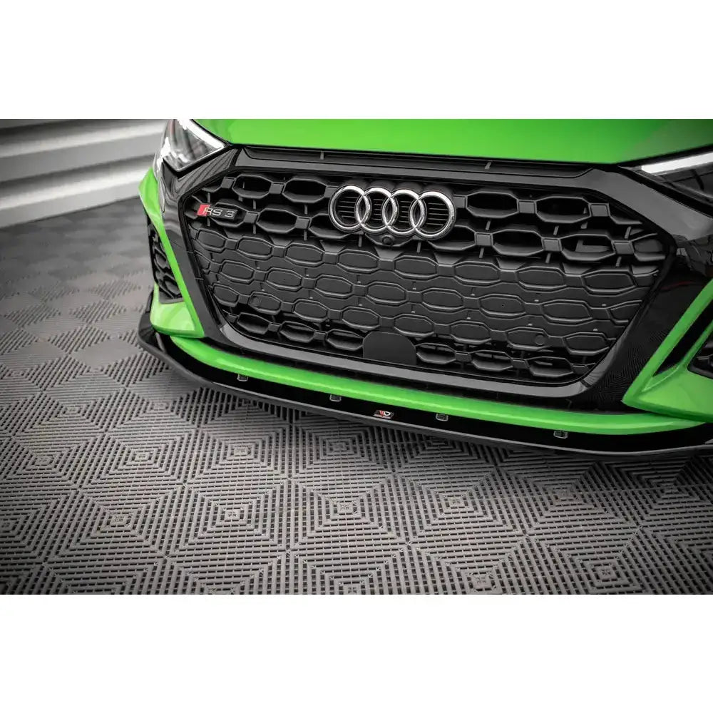 Frontsplitter på Audi RS3 8Y med sort grill, RS3-emblem og sporty støtfanger sett fra skrå vinkel.