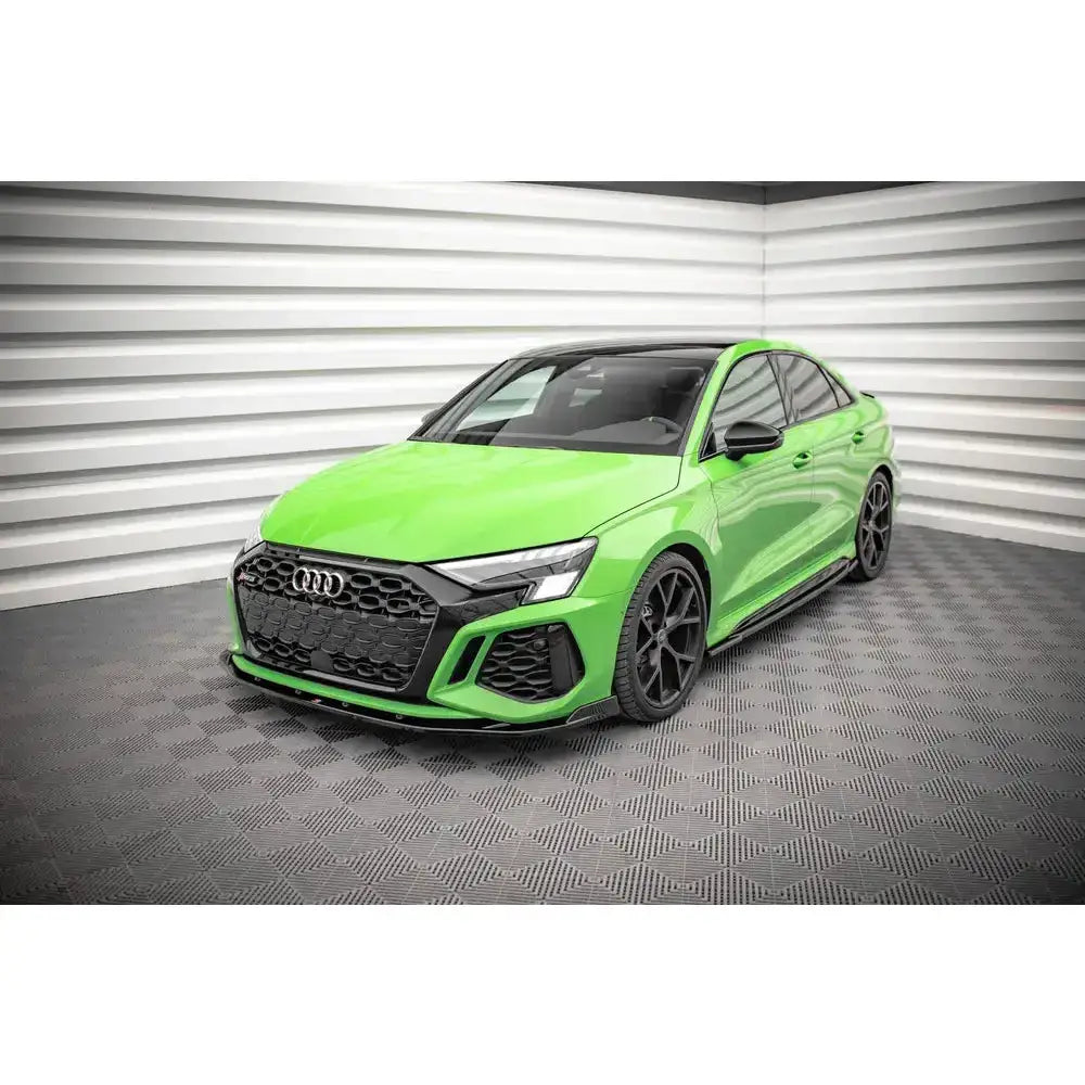 Front lip på Audi RS3 8Y V.2 i limegrønn med sorte detaljer, sett skrått forfra i lyst rom.