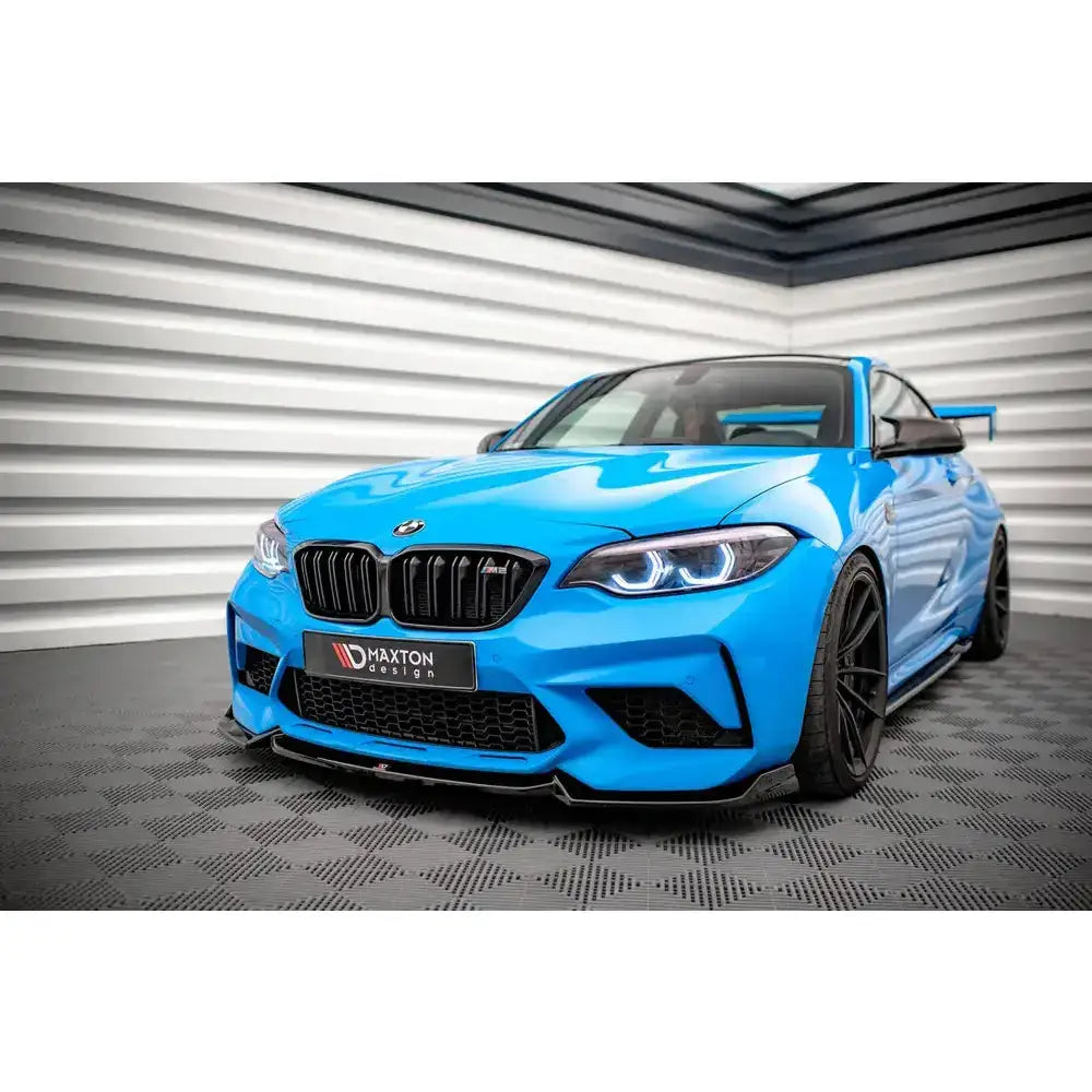 Front splitter på BMW M2 Competition F87 med sort frontspoiler og brede sorte felger, sett forfra.