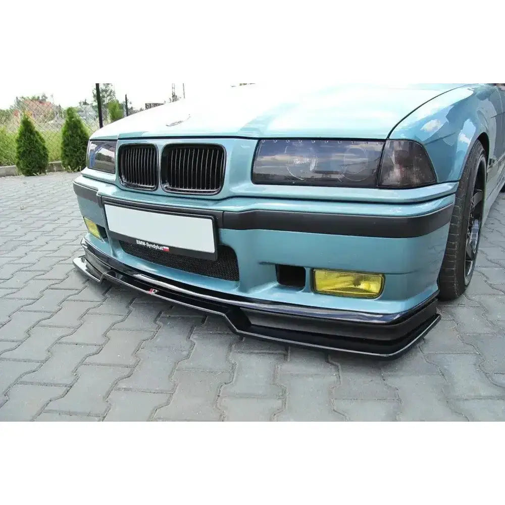 Frontspoiler til BMW M3 E36 V.2 i sort plast montert på lyseblå bil med gule tåkelys.