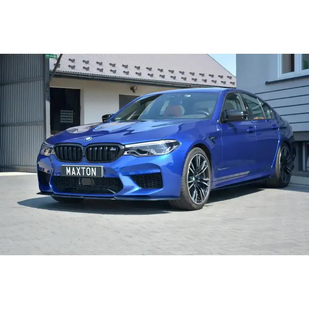 Frontleppe på blå BMW M5 F90 V.2 med sorte detaljer, parkert foran bygning.