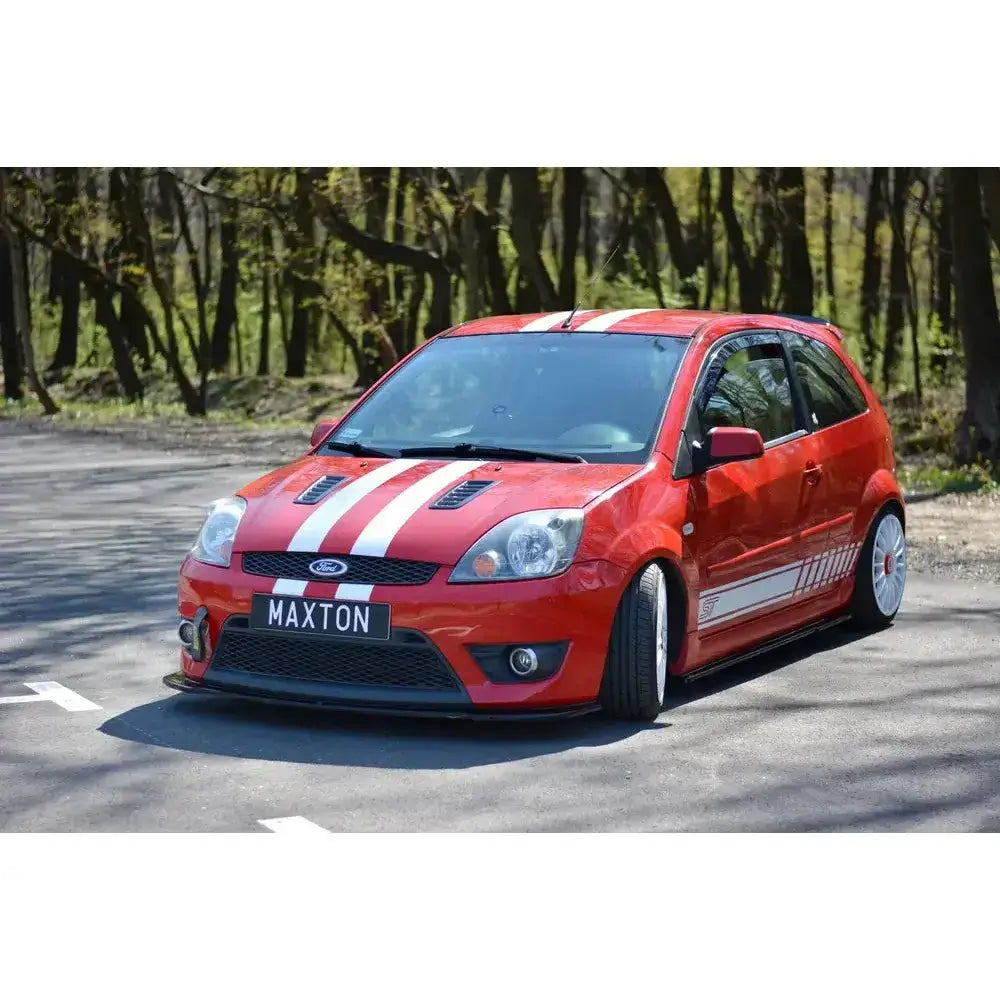 Frontleppe på Ford Fiesta Mk6 St V.2, rød med hvite striper, sett skrått forfra utendørs.