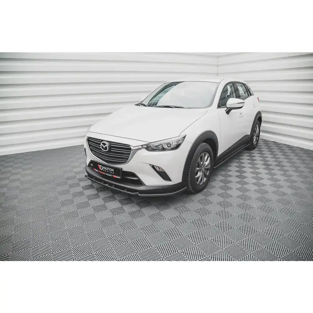 Frontleppe på hvit Mazda CX-3 V.2 SUV med mørke felger og sølvfarget grill, innendørs bak lyst teppe.