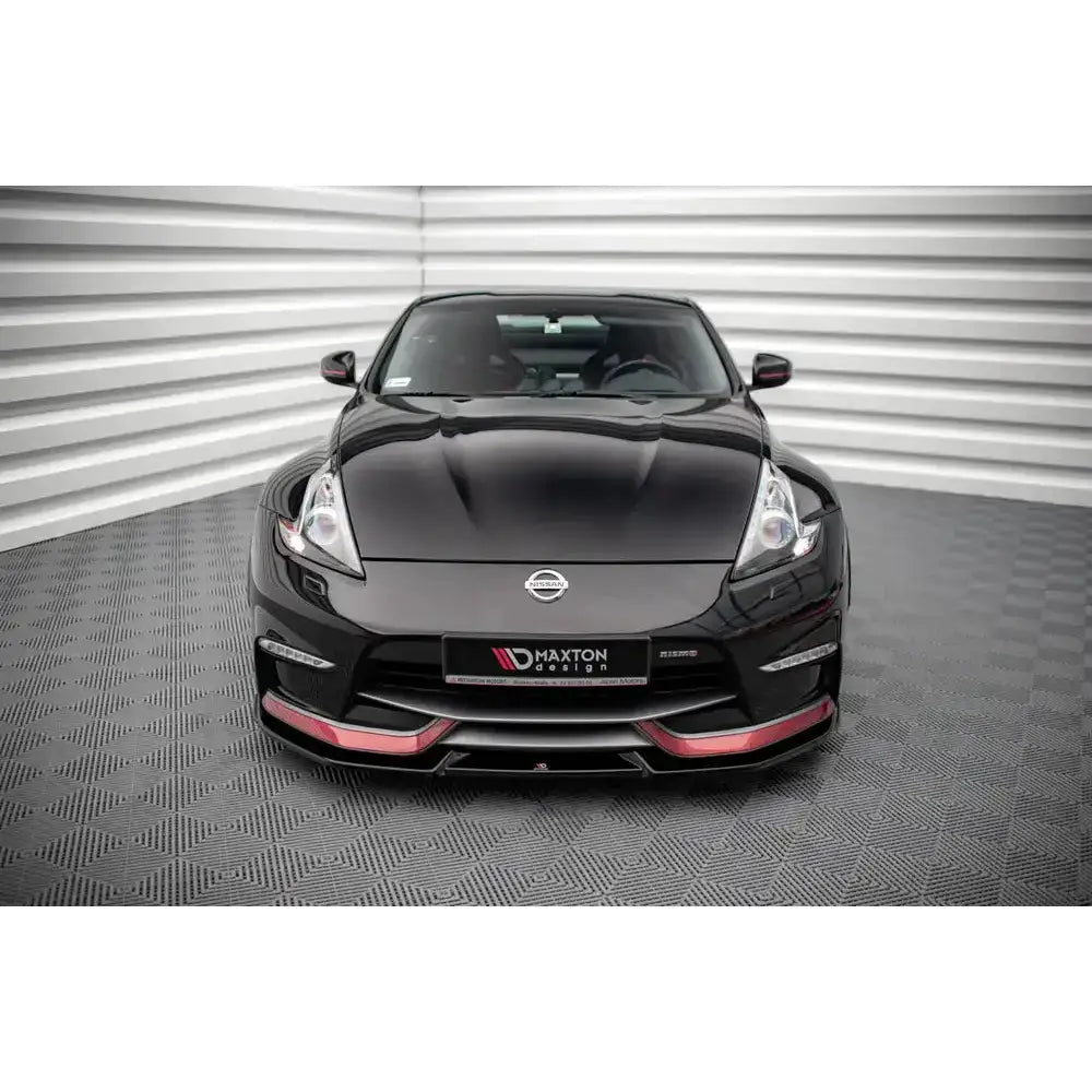 Frontleppe på svart Nissan 370Z Nismo Facelift med røde detaljer, sett forfra i lyst rom.