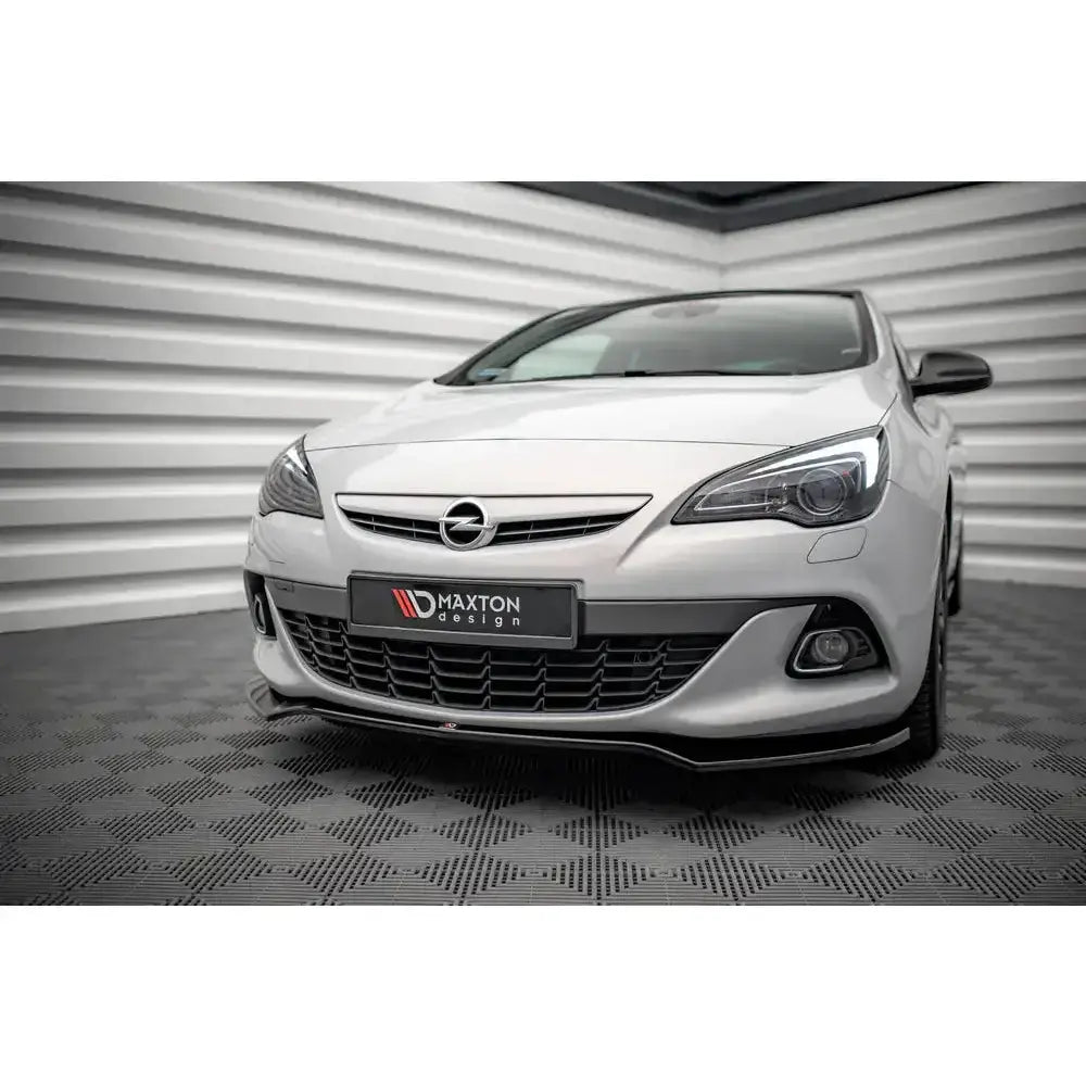 Front splitter på hvit Opel Astra GTC OPC-Line J med sorte detaljer, sett forfra mot lys, riflet vegg.