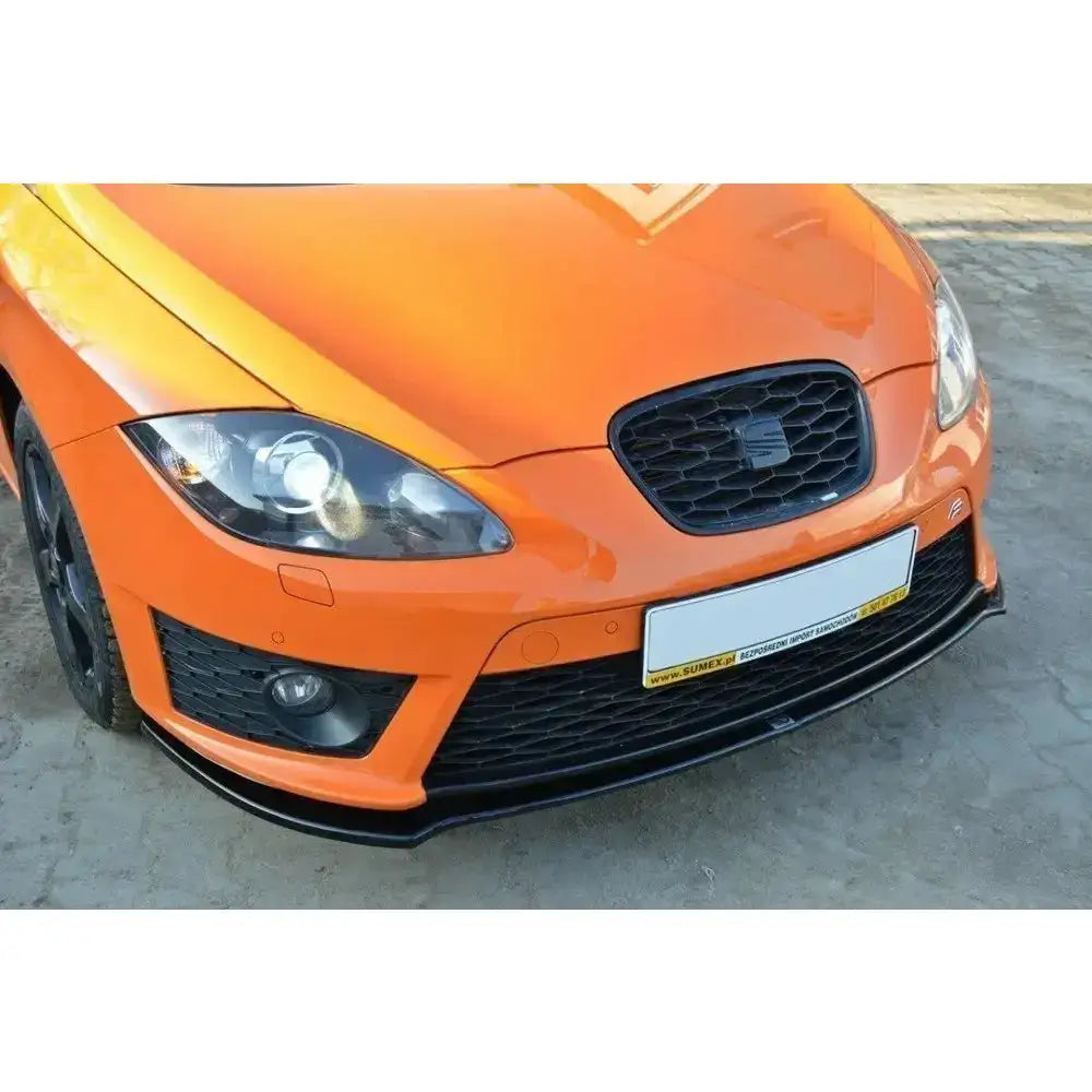 Spoiler på oransje Seat Leon Mk2 Cupra med sort grill og frontsplitter sett nedenfra i skrå vinkel.