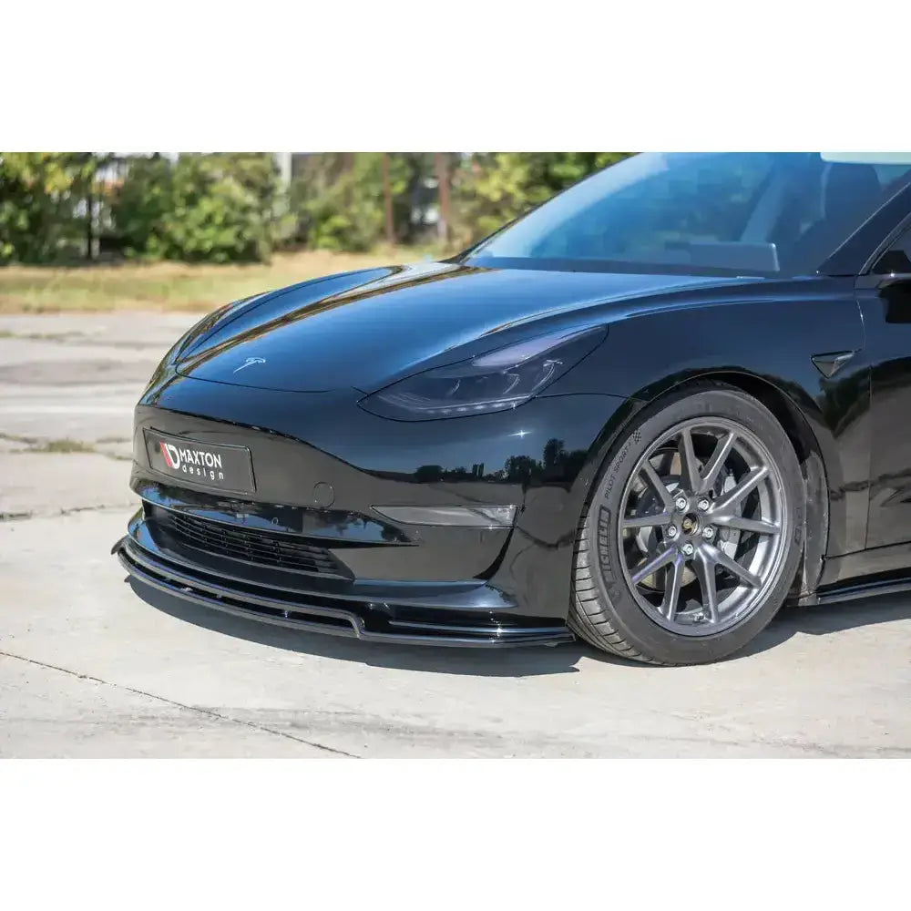 Spoiler på Tesla Model 3 V.2, sort bil med lav frontspoiler og sporty felger utendørs.