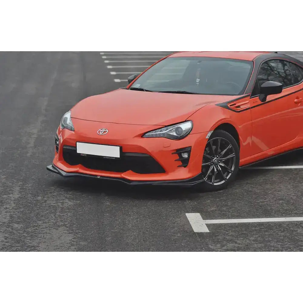 Frontleppe på oransje Toyota GT86 Facelift V.2 med svart frontsplitter og svarte felger, sett skrått forfra.