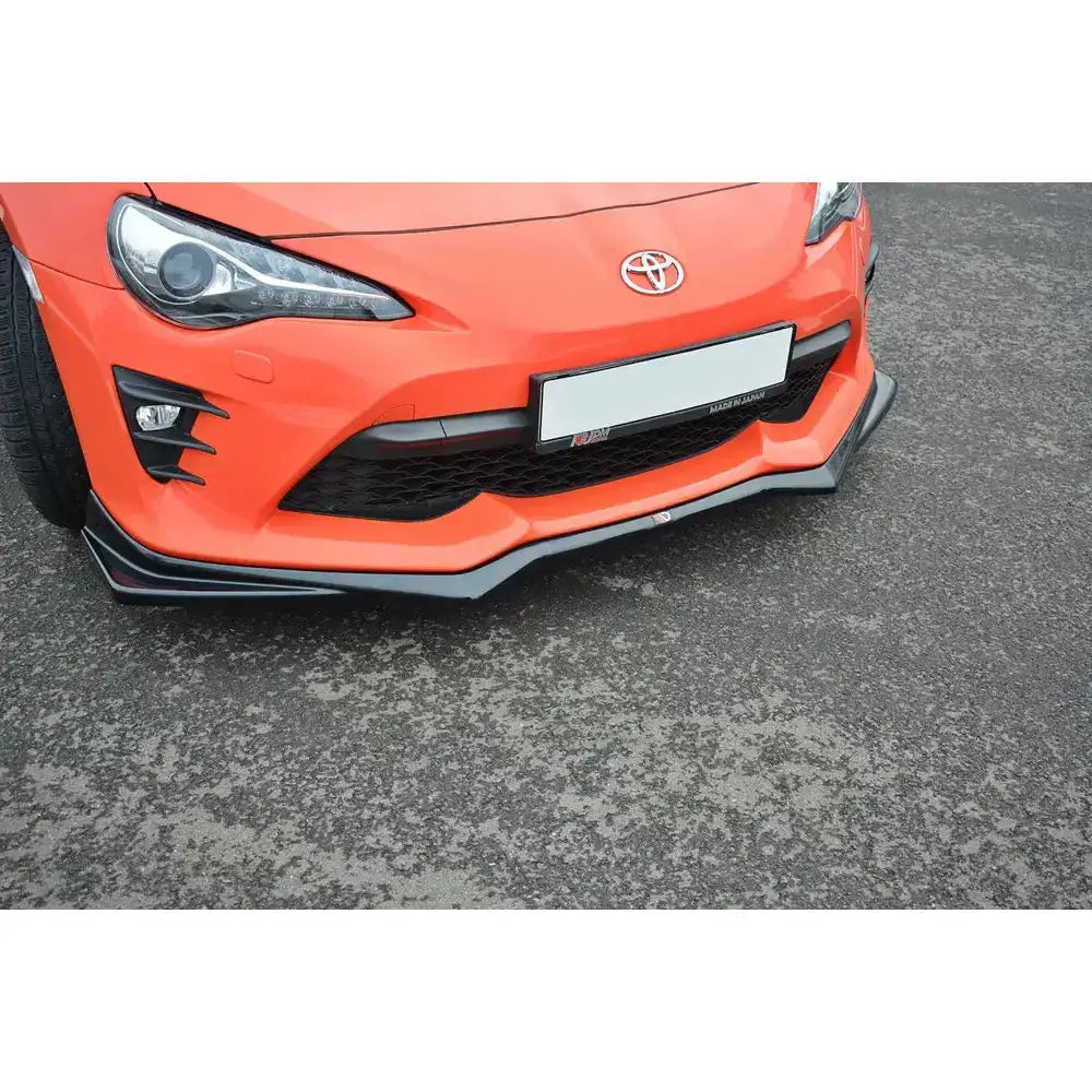 Spoiler til Toyota GT86 Facelift V.2, svart frontsplitter montert under støtfanger på oransje bil.