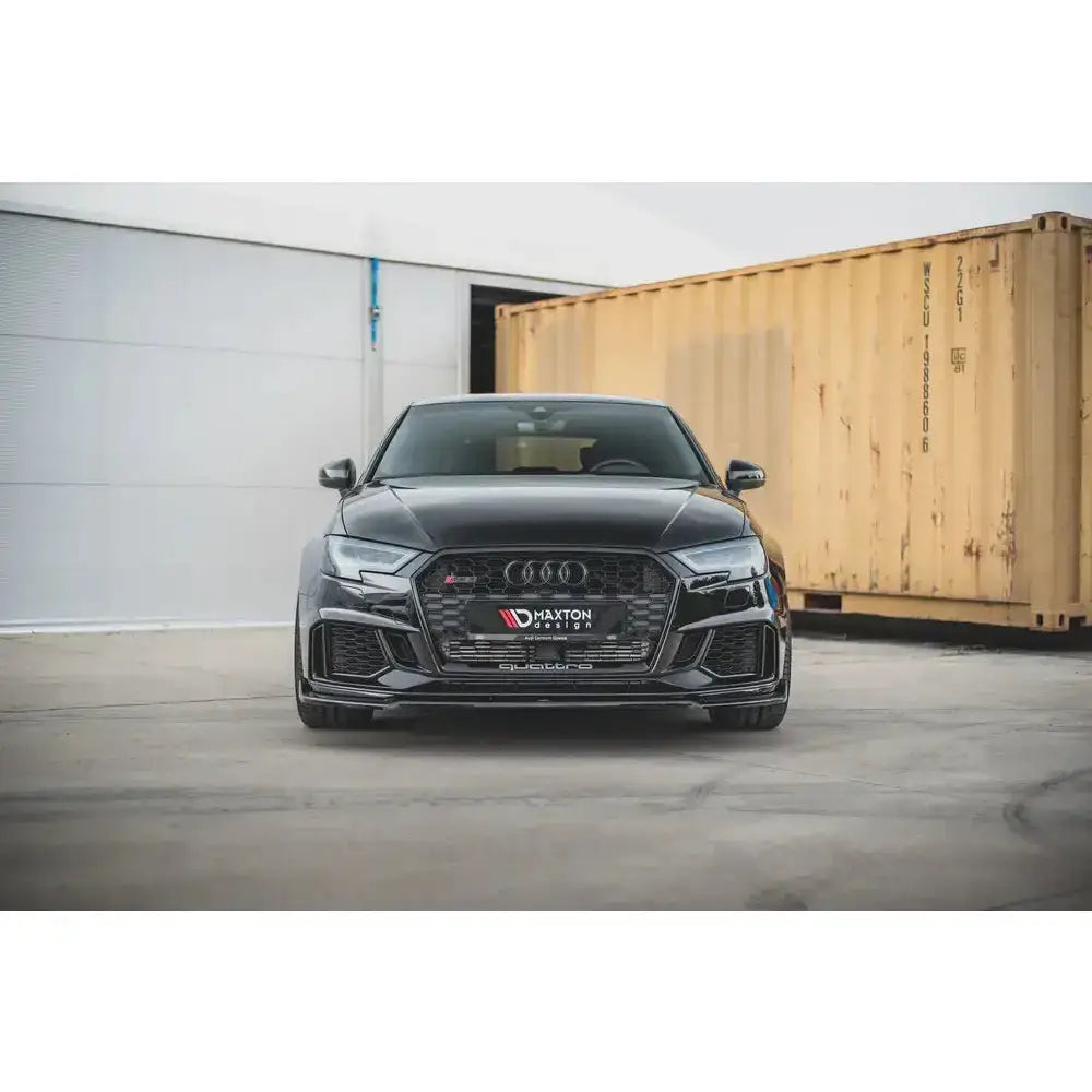 Front splitter Audi RS3 8V FL Sportback V.3 montert på svart bil foran beige container.