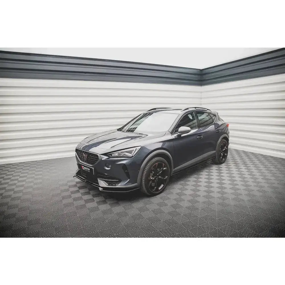 Frontleppe på Cupra Formentor V.3 20- SUV i mørk grå med svarte felger, sett fra siden i lyst rom.