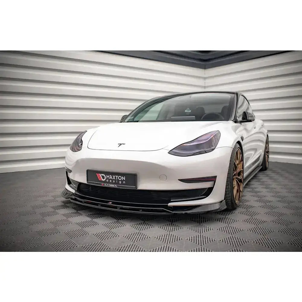 Front splitter på hvit Tesla Model 3 V.3 med bronsefargede felger og svarte detaljer, fotografert innendørs.