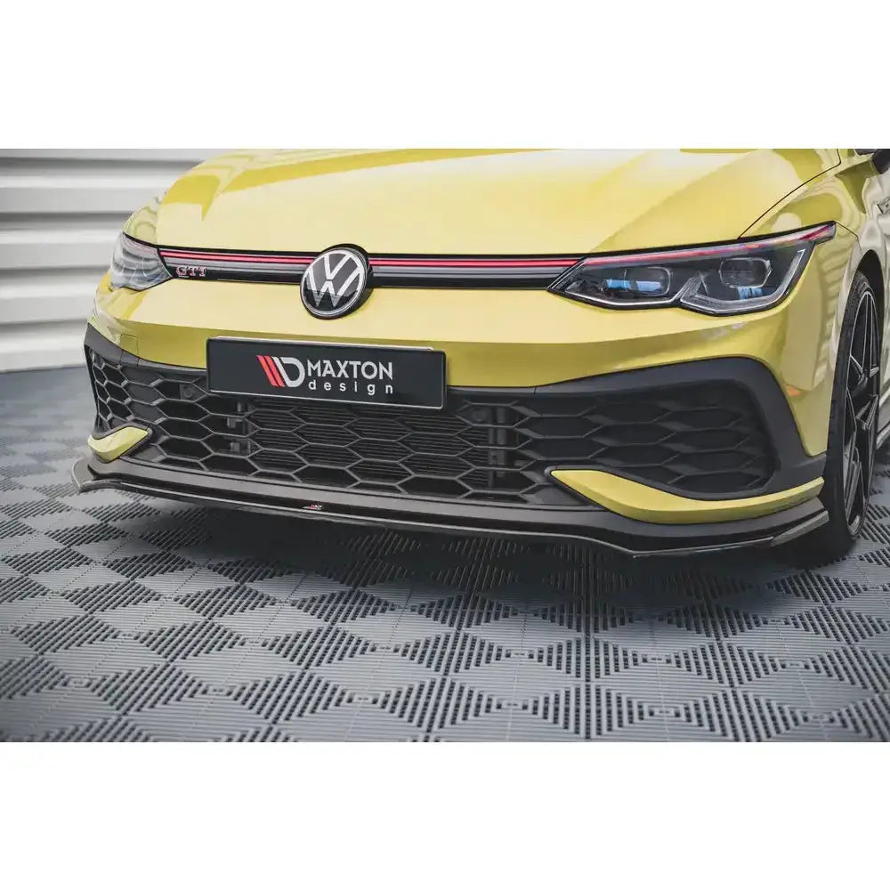 Frontspoiler på Volkswagen Golf 8 GTI Clubsport V.3, svart med røde detaljer, sett forfra innendørs.