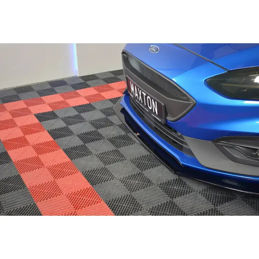 Front splitter på blå Ford Focus ST MK4 med synlig frontspoiler og rutemønstret gulv i sort og rødt.