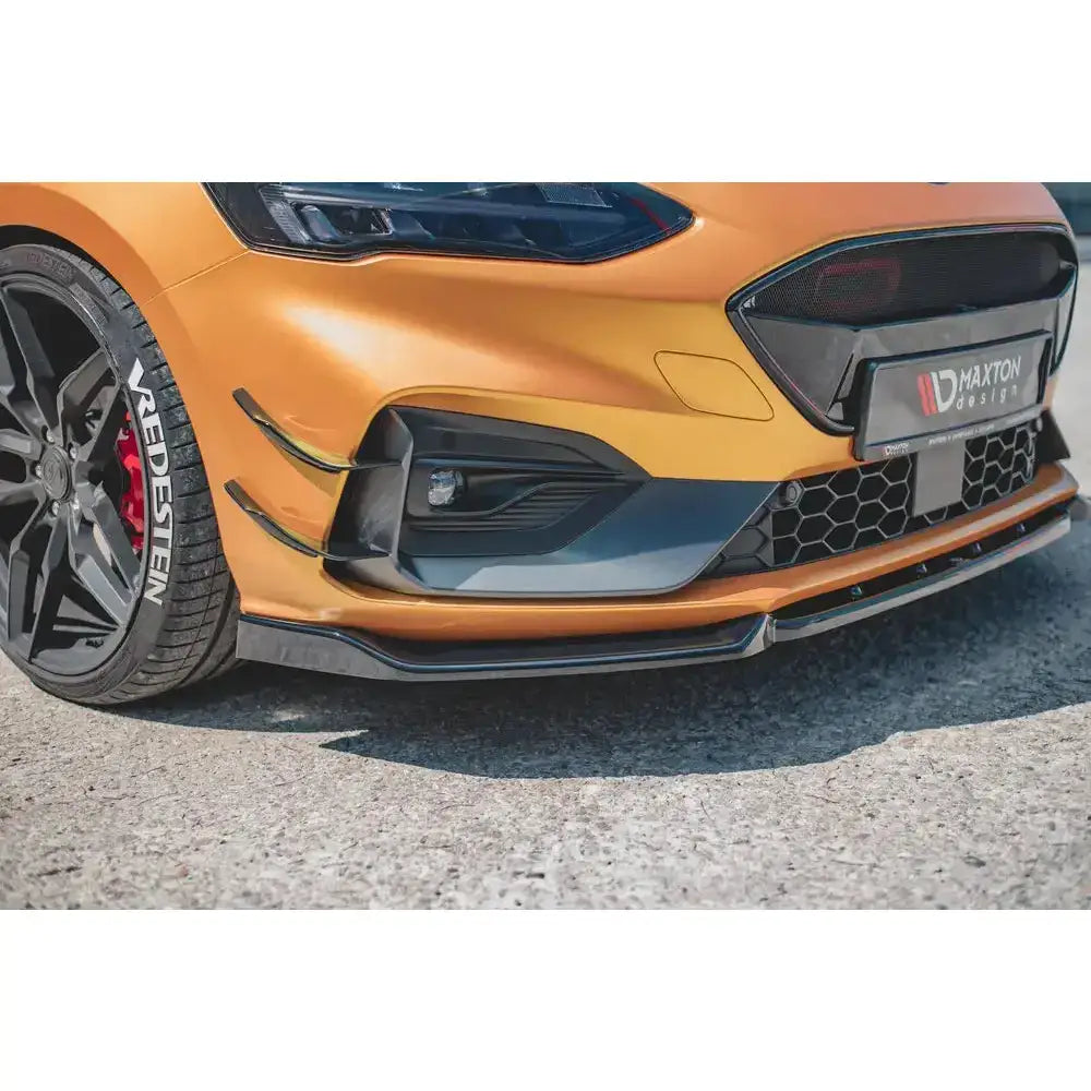 Front splitter på oransje Ford Focus ST med sorte detaljer, aluminiumsfelger og Maxton Design-logo.