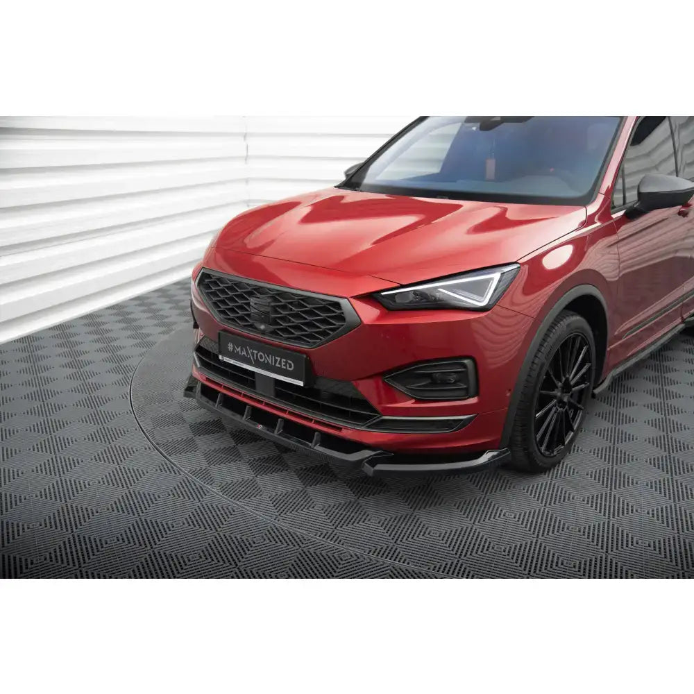 Spoiler til Seat Tarraco FR Mk1 V.1, sort frontsplitter på rød bil sett skrått forfra med sportslige detaljer.