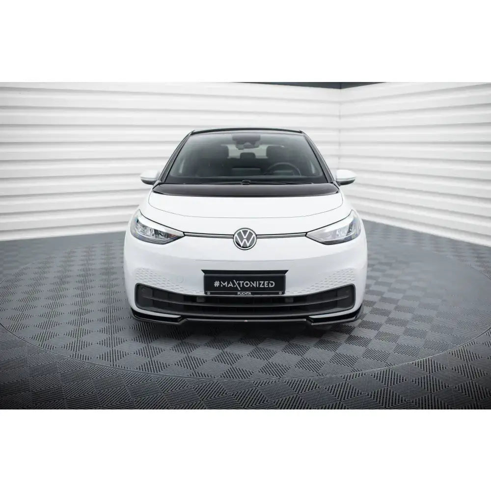 Spoiler Volkswagen ID3 Mk1 V.1 montert foran på hvit bil, sett forfra med synlig VW-logo.