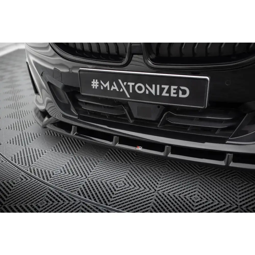 Front splitter BMW 2 Coupe G42 V.2 sett forfra og nedenfra, sort glanset med markerte linjer mot mønstret gulv.