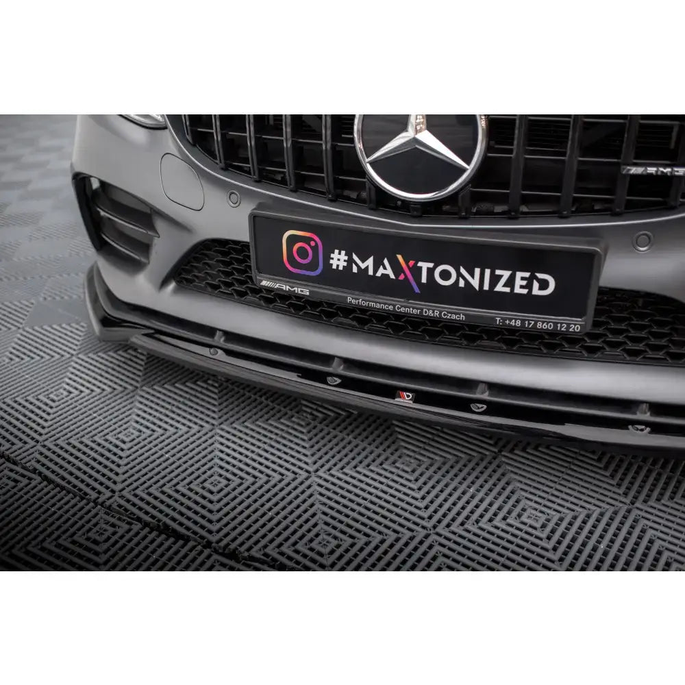 Front splitter på sort plast montert på grå Mercedes C43 AMG, nærbilde med glansede detaljer og logo.