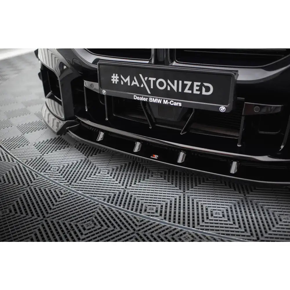 Front splitter BMW M2 G87 V.3 i sort, blankt materiale sett forfra og nedenfra på bil med dekorativt skilt.