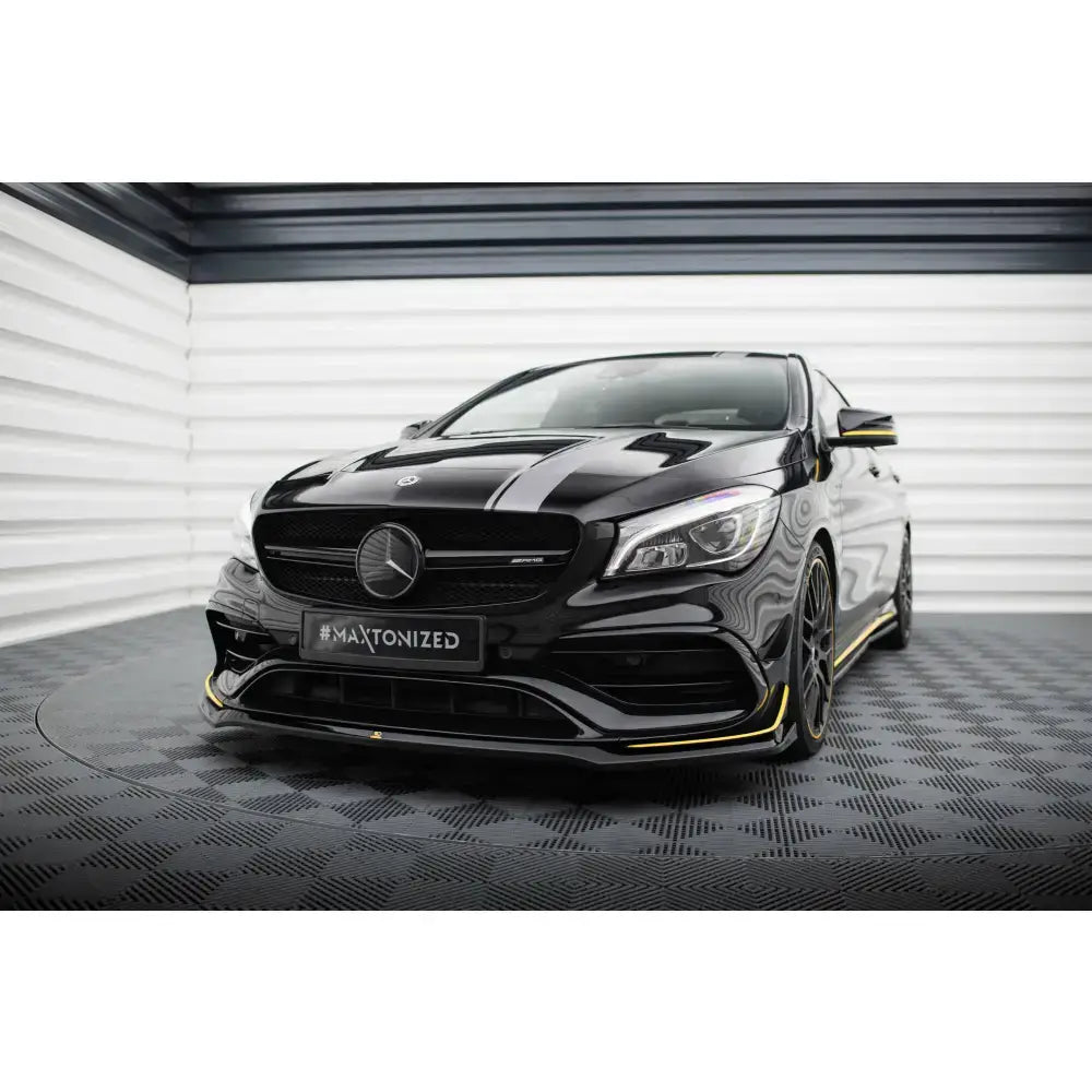 Front splitter på Mercedes CLA 45 V.3 Aero C117, sort med gul kant, sett forfra mot lyse vegger.